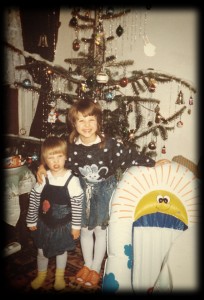 Klein-Juliane mit begeisterter Schwester vor dem Weihnachtsbaum
